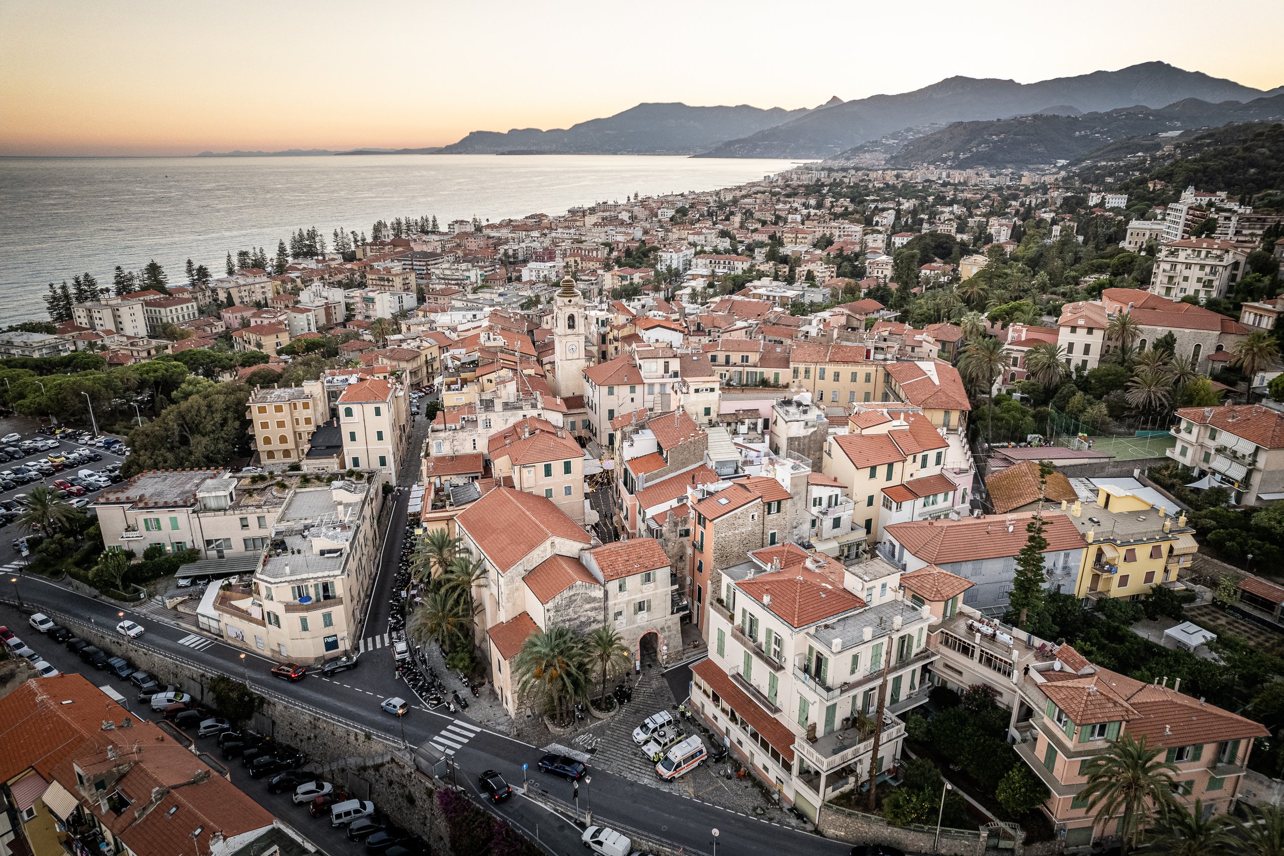 Vista aerea di Bordighera Alta al tramonto, con i tetti in coppi, le mura, il campanile e la costa verso la Francia