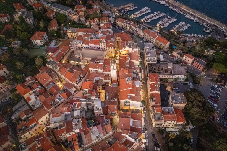 Bordighera Alta dall'alto all'imbrunire, con i vicoli illuminati, il campanile, il porto e il mare