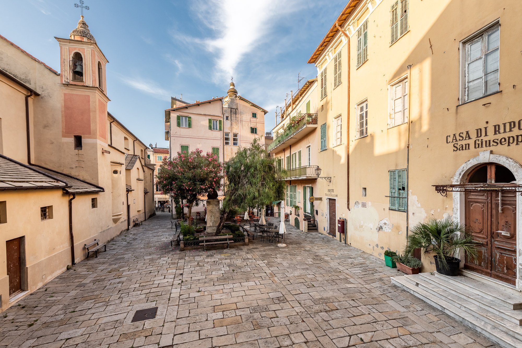 Piazza di Bordighera Alta con la Casa di Riposo San Giuseppe, il campanile, gli alberi e il lastricato in pietra