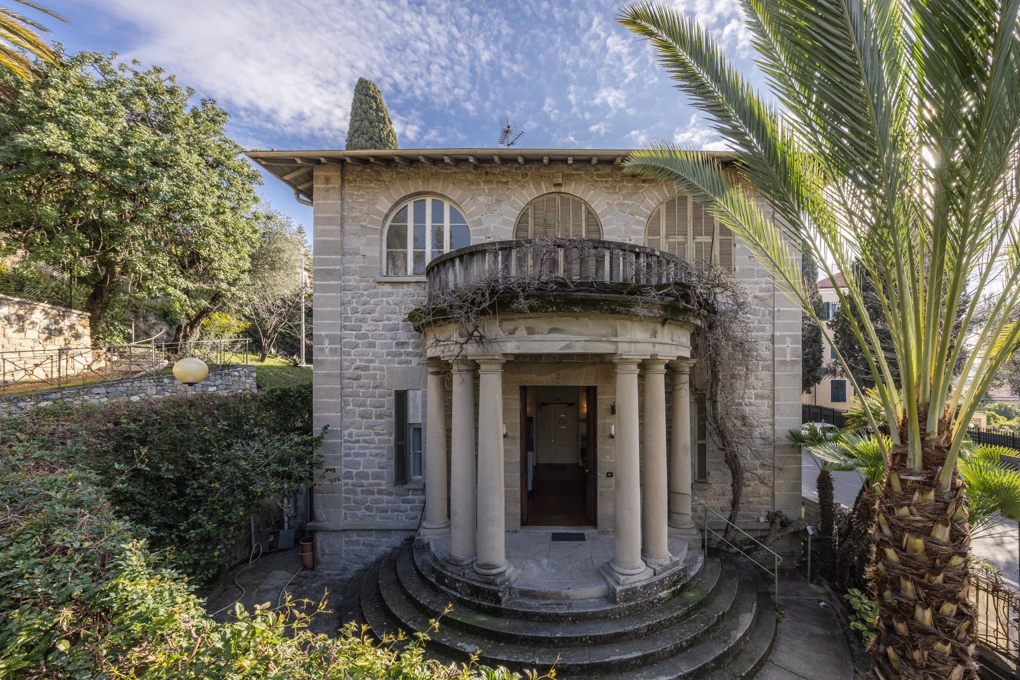 Villa in pietra della Biblioteca Civica Internazionale di Bordighera con l'ingresso a tempietto su colonne, scalinata e palme