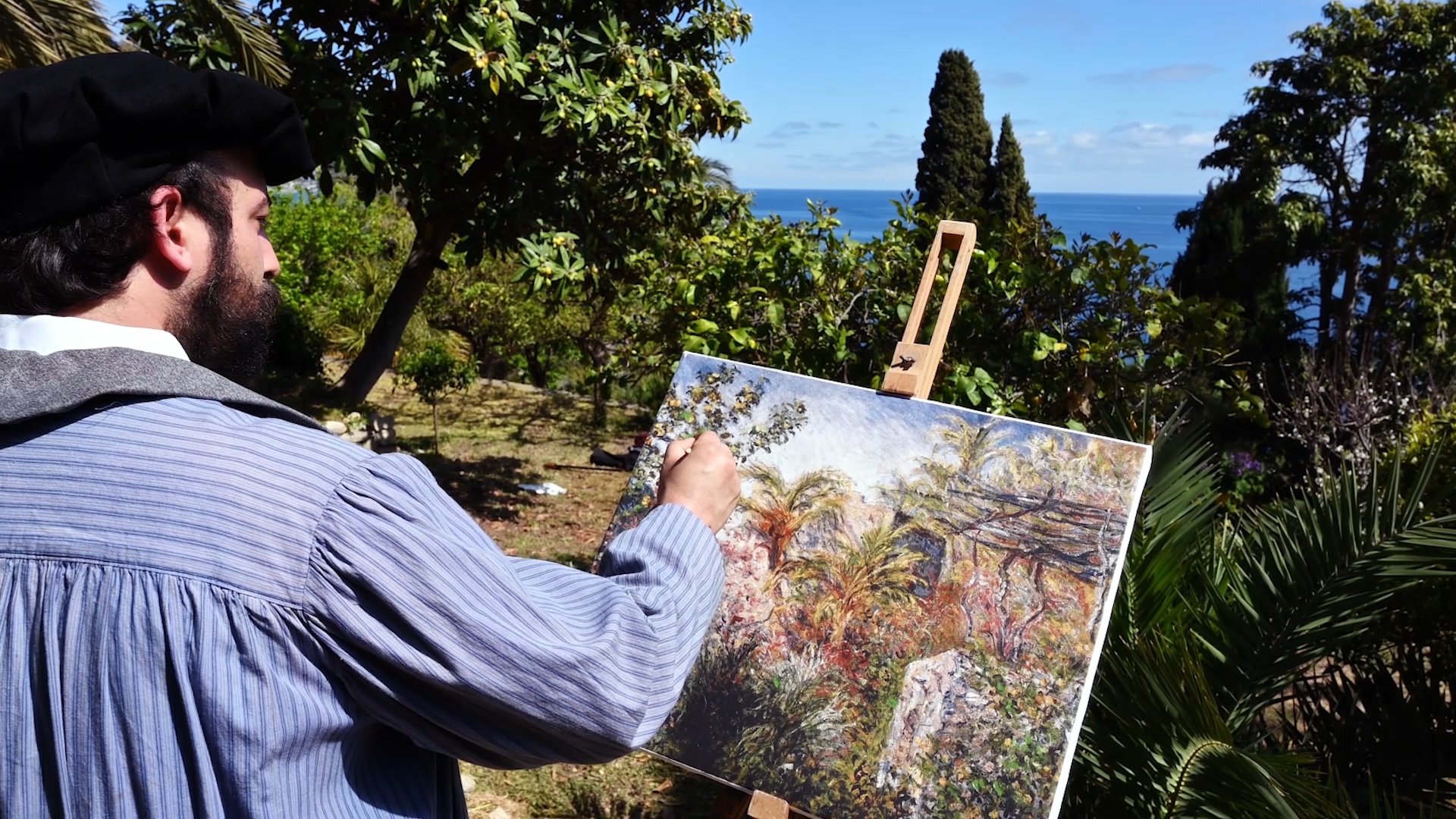 Pittore in abiti ottocenteschi che dipinge un giardino su una tela al cavalletto, con il mare sullo sfondo