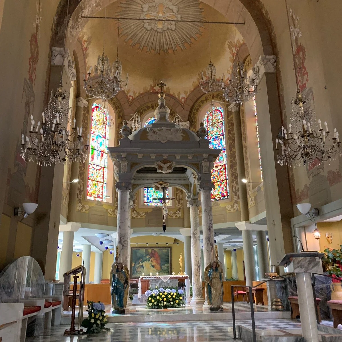 Das Innere der Kirche Terrasanta in Bordighera mit dem Baldachin über dem Altar, den Kronleuchtern und den Glasfenstern