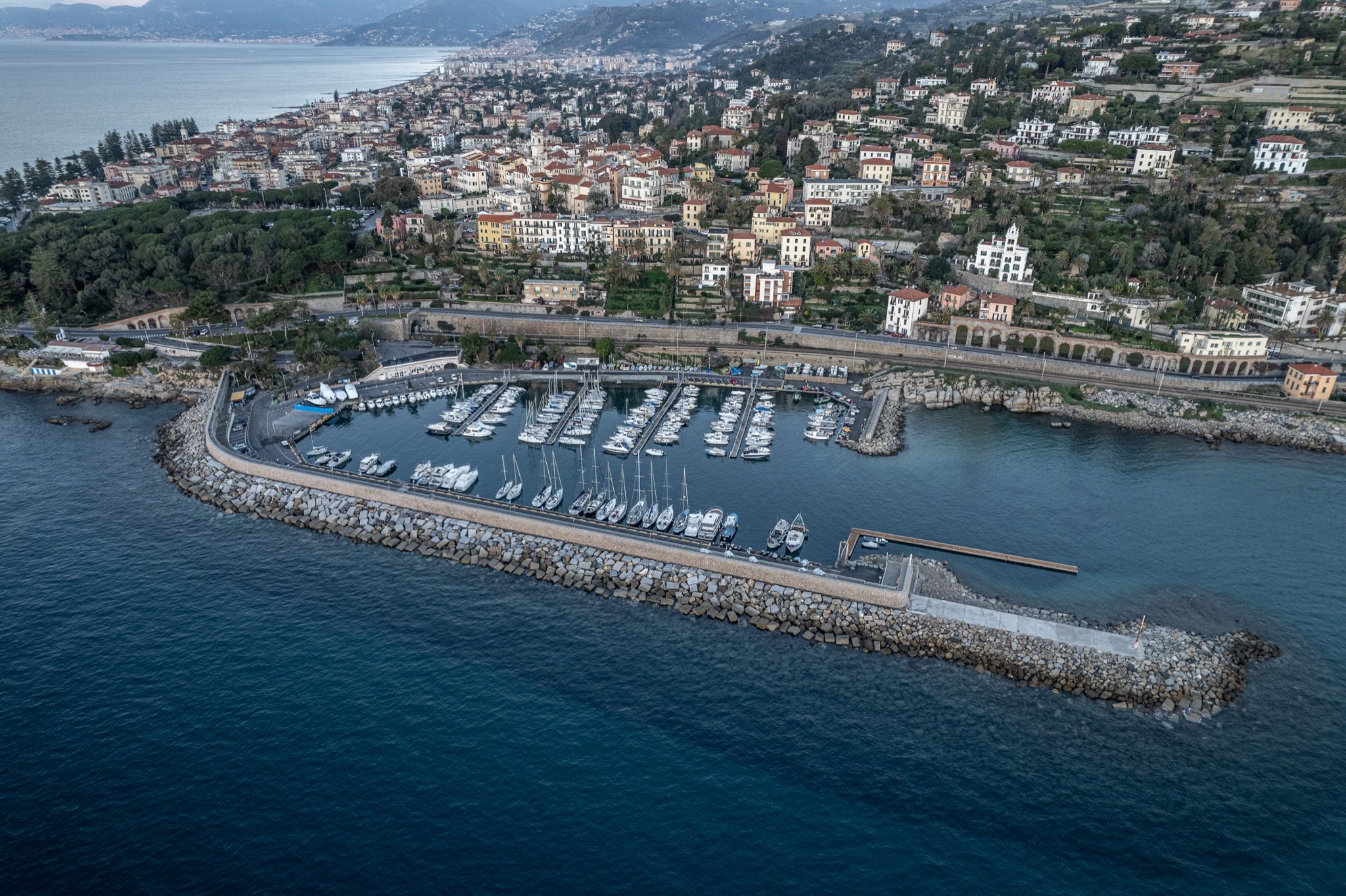 Vista aerea del porto turistico di Bordighera con la diga, le barche ormeggiate e la città sulla collina