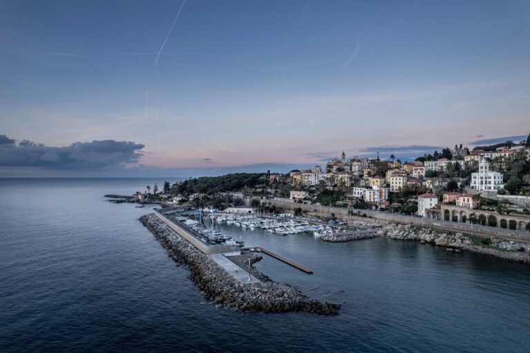 Luftaufnahme des Hafens von Bordighera mit Mole, Booten und Bordighera Alta auf dem Hügel bei Sonnenaufgang