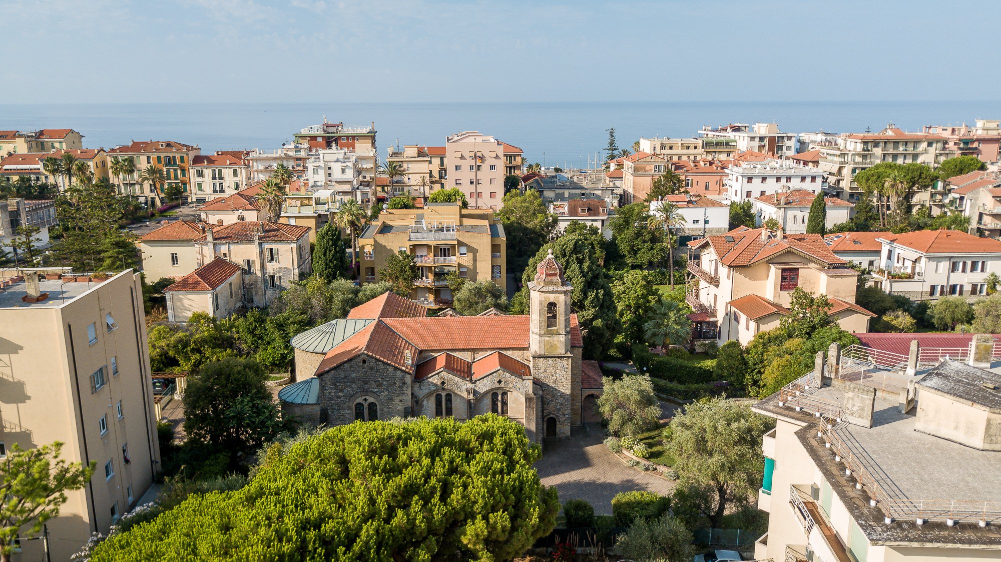 Vista aerea dell'ex Chiesa Anglicana con il campanile tra ville e palazzi di Bordighera, con il mare all'orizzonte
