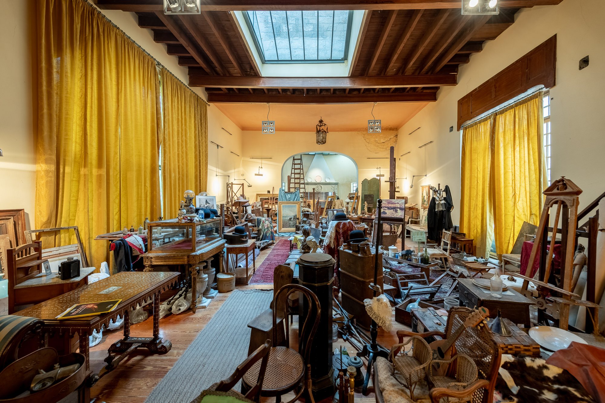Interno dell'atelier di Pompeo Mariani con lucernario, tende gialle, cavalletti, mobili antichi e oggetti del pittore