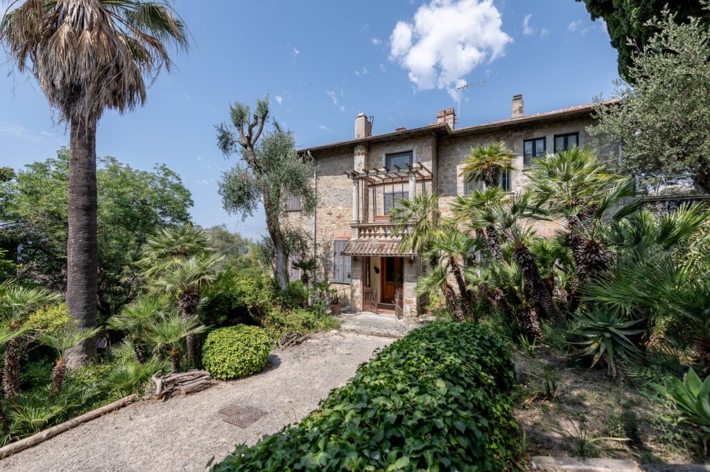 La villa in pietra della Fondazione Pompeo Mariani immersa nel giardino di palme, olivi e piante mediterranee sotto il cielo azzurro