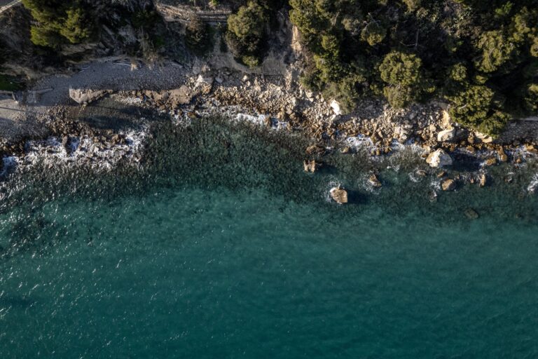Kleine Felsbucht von oben mit smaragdgrünem Wasser und mediterraner Macchia an der ligurischen Küste