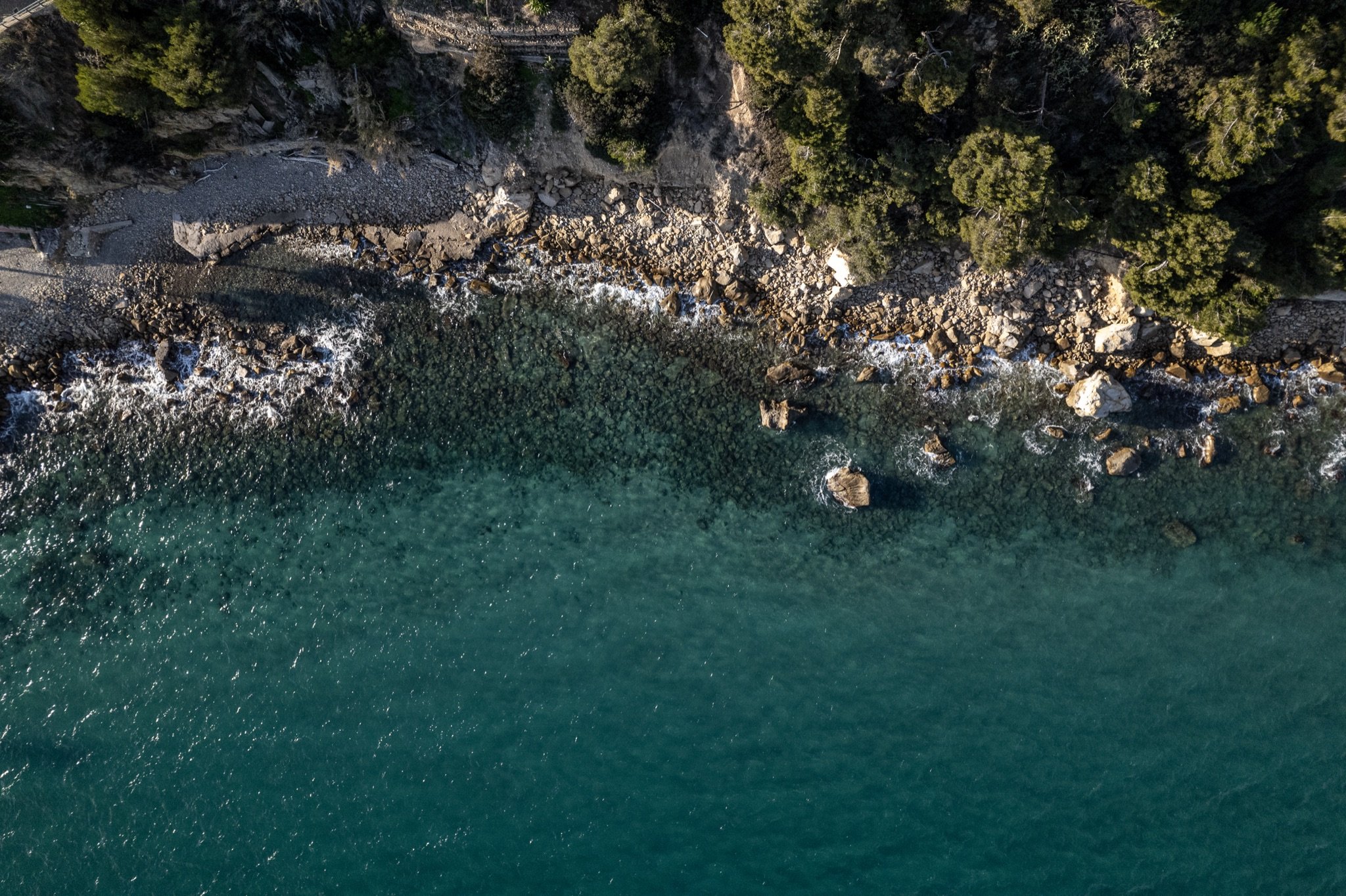 Kleine Felsbucht von oben mit smaragdgrünem Wasser und mediterraner Macchia an der ligurischen Küste