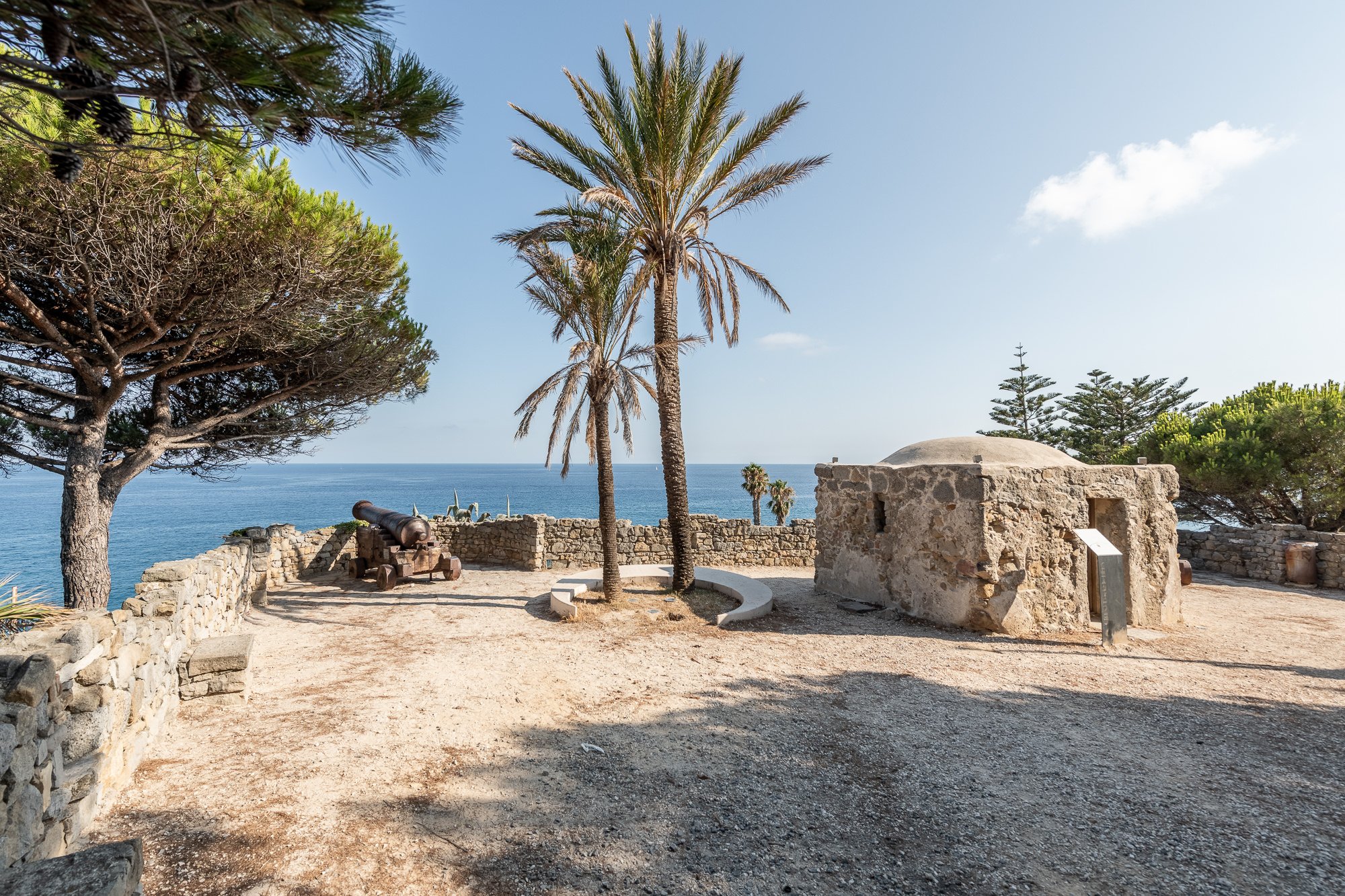 Il Marabutto con la sua piccola cupola in pietra, un cannone sulla terrazza sterrata e palme alte davanti al mare