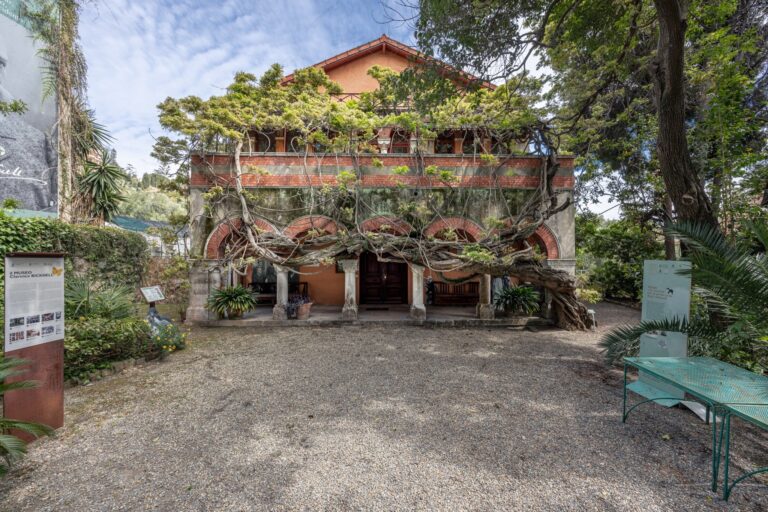 Facciata del Museo Bicknell con il portico ad archi coperto dal glicine, il piazzale in ghiaia e un tavolo verde