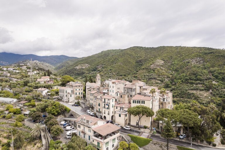 Aerial view of the village of Sasso among green hills, olive trees and scattered houses, with mountains in the background