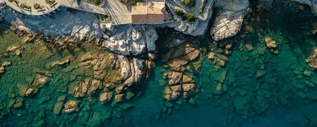 Veduta aerea degli scogli e del mare turchese sotto Capo Sant'Ampelio